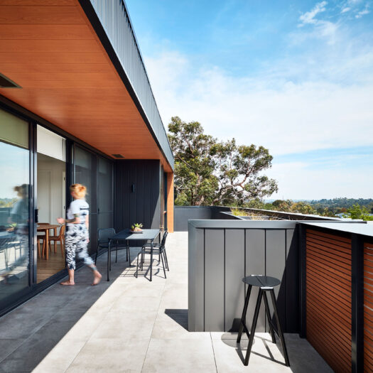 Bayswater Women's Housing elevated balcony view with figure entering sliding glass doors - building photographer example / concept