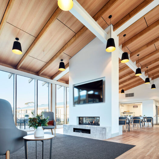 TLC Aged Care Homestead Estate dining area with lounge, tv and fireplace and timber ceiling with pendant lights - building photographer example / concept