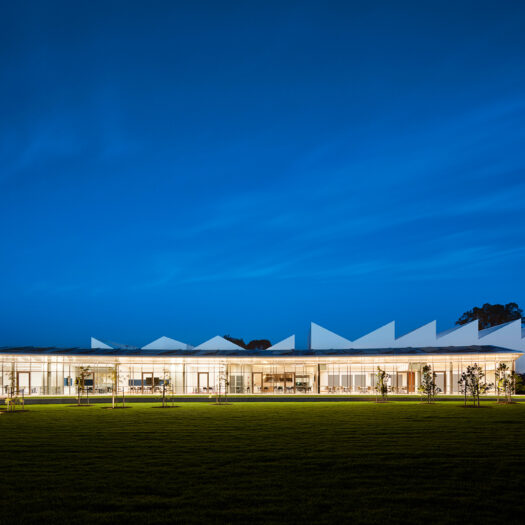Nunawading Community Hub glazed facade at night with asymmetric sawtooth roofline rising up behind - structure photographer example / concept