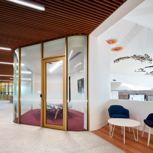 Nunawading Community Hub enclosed glass meeting room from hallways with public seating and artwork hanging from ceiling - structure photographer example / concept