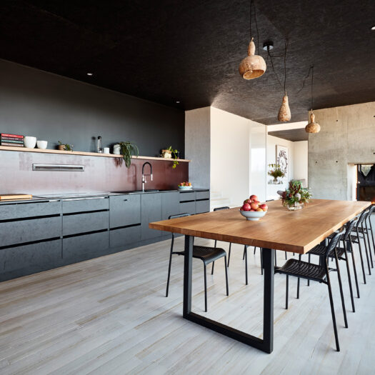 kitchen with black cabinets, timber table and fireplace - building photographer example / concept