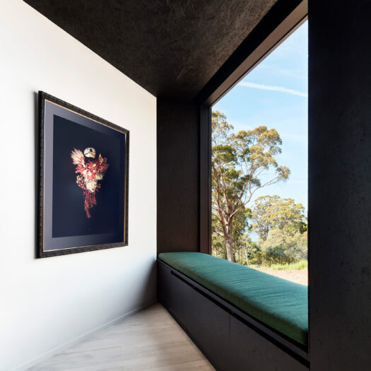 dark green soft window seat with view to trees, artwork on left - building photographer example / concept