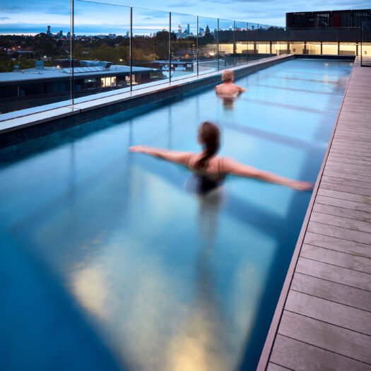 Hawthorn Park rooftop pool at dusk with two people swimming - building photographer example / concept