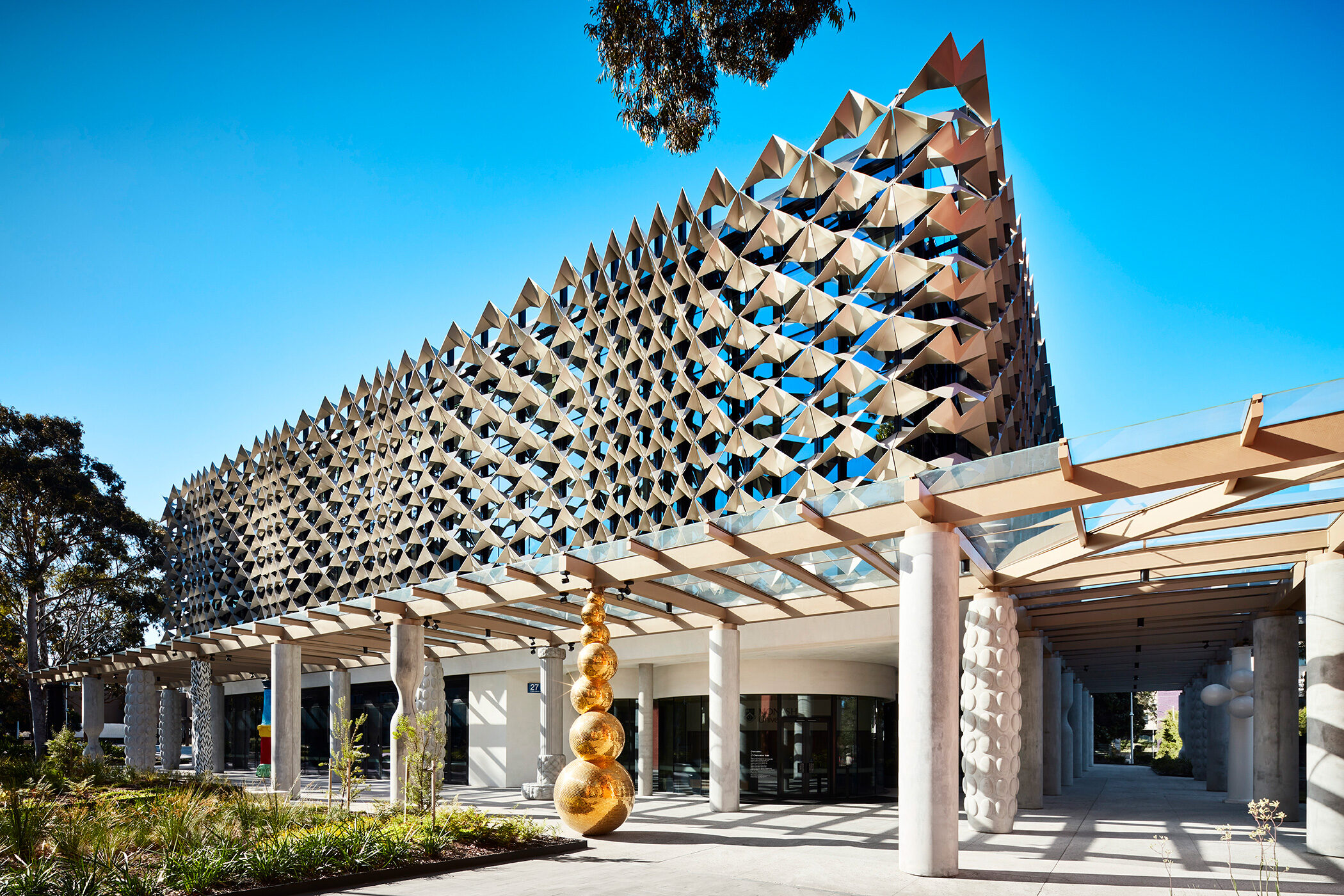 Monash University Chancellery view of facade with steel mesh featuring brilliant gold disco ball column catching light - University example / concept